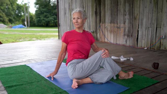Silver haired senior woman do yoga pose half lord of the fishes.