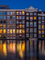 Historic buildings on the Damrak canal in the centre of beautiful Amsterdam at night.