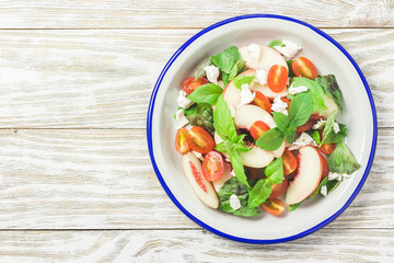 Peach tomato basil salad on white rustic background. Top view, space for text.