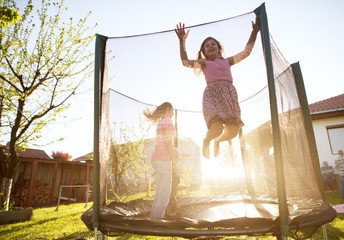 Three adorable playful kids are jumping on trampolines on a sunny day
