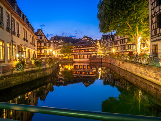 Fototapeta na wymiar Sunset along the Ill River in Petite France areas of Strasbourg in the Alsace region of France. The homes are the traditional half timbered houses visible all over this area of France.
