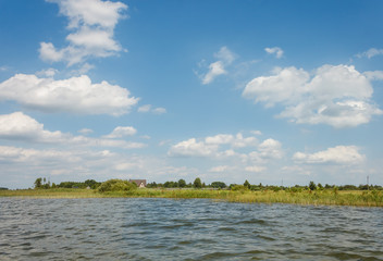 Lake on a sunny day with blue sky and white clouds. View from the water