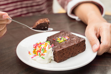 Woman eating brownie with cream.