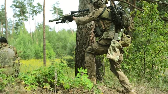 Airsoft man with guns stand back to back. Soldiers stand on hill and go out after