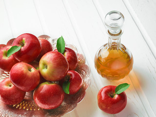 Decanter of apple cider vinegar and an old metal bowl full of red apples