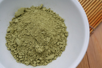 Green Matcha tea powder in a bowl on wooden background. Powdered matcha green tea on wooden table
