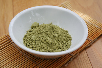 Green Matcha tea powder in a bowl on wooden background. Powdered matcha green tea on wooden table