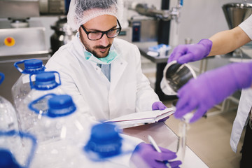 Cheerful lab employee taking notes of test experiments.