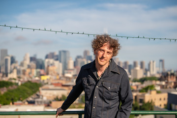 Attractive forty something man enjoying a summer evening on a rooftop in Chicago, with the beautiful skyline beyond.