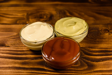 Different sauces in glass bowls on wooden table