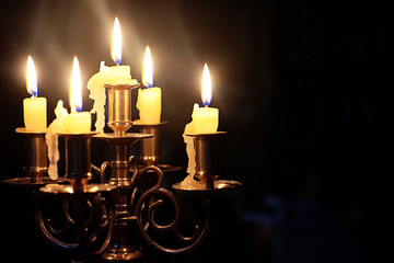 vintage bronze chandelier with five lit candles on the table glowing in the dark, soft focus