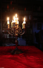 vintage bronze chandelier with five lit candles on the table glowing in the dark, soft focus