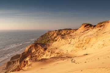 Panorama view of endless sand dunes in sunset sun light and blue ocean. Rubjerg Knude Lighthouse, Lønstrup in North Jutland in Denmark, Skagerrak, North Sea