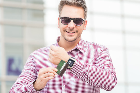 Man making payment by using smartwatch and debit card outdoors.
