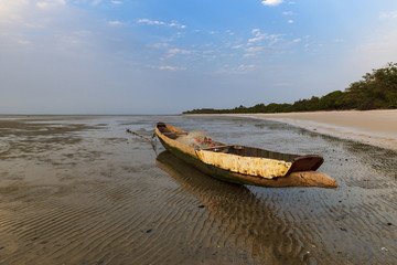 View of a traditional fishing canoe at the beach in the island of Orango at sunset, in Guinea Bissau. Orango is part of the Bijagos Archipelago; Concept for travel in Africa and summer vacations