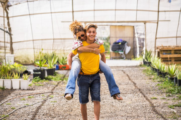 young beautiful teenager play with his mother middle age pretty woman carrying her to his back. couple mother son having fun together like a perfect family in outdoor leisure activity. happy people