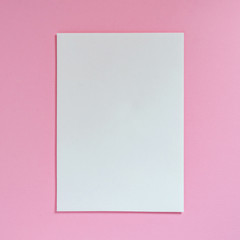 Sheet of white empty paper on a pink background, top view. Flat lay