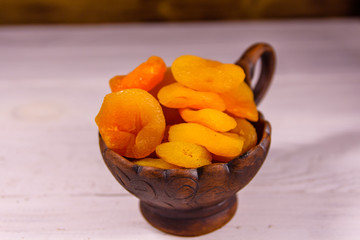 Ceramic bowl with dried apricots on wooden table