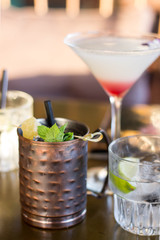 Cocktail in an iron cup in the foreground behind a cocktail in a glass