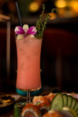 Beautiful pink cocktail adorned with orchid and green twig