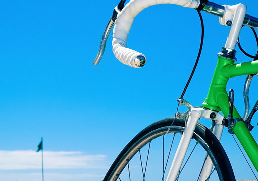 a green race cycle with white handlebar. cycling race concept with a flag on the horizon.