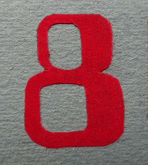 Decorative hand made red velvet textured number eight on the gray background wall  
