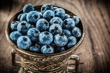 Blueberries in vintage metal bowl on grunge board