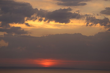 Fototapeta premium Beautiful sunset with clouds of orange and yellow in the ocean, the river