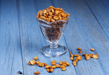 Glass dish filled with peanuts.