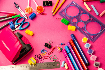 Felt pens, pencils, clips of different colors on a pink background