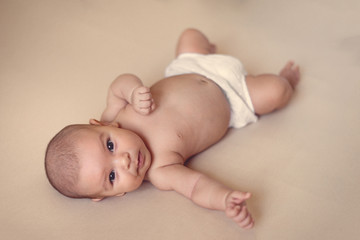 cute newborn baby girl lying on simple isolated beige background