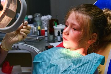 A little girl at the dentist is crying with tears at a doctor's appointment while treating a tooth.