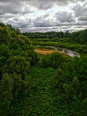 Fototapeta na wymiar Река среди деревьев на фоне облачного неба River among trees against a background of cloudy sky