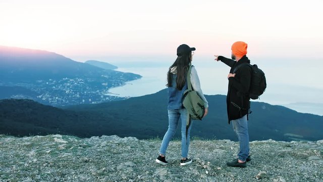 Team of hipster backpacker pointing talking about amazing sea harbour standing on peak of mountain