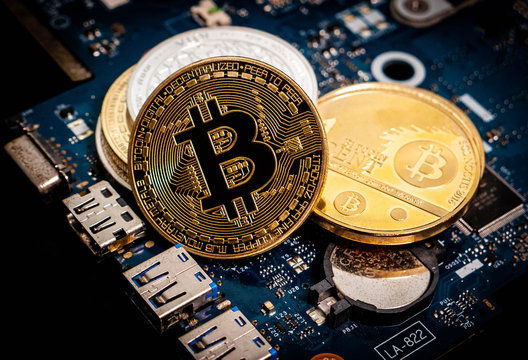Golden Bitcoin coins on a blue computer motherboard with a black background.