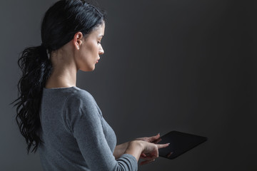 Young woman using her tablet on a gray background