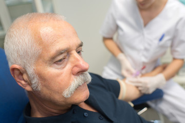 nurse doing blood test for senior man with diabetes