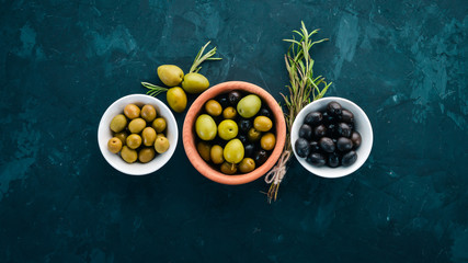 Olives in a plate and rosemary. On a stone background. Free space for text.