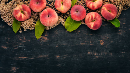 Flat peach with green leaves On a black wooden background. Top view. Free space for your text.