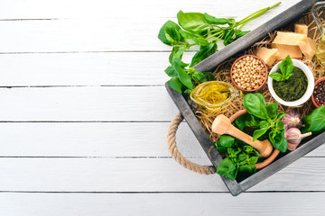 Ingredients for cooking Pesto sauce in a wooden box. Basil, parmesan cheese, olive oil, pine nuts,...