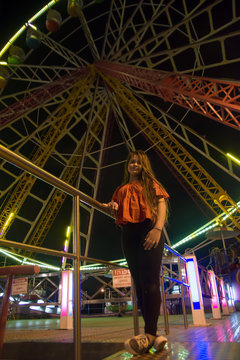 Girl is staying near Ferris wheel in the evening park and looking on colorful eye