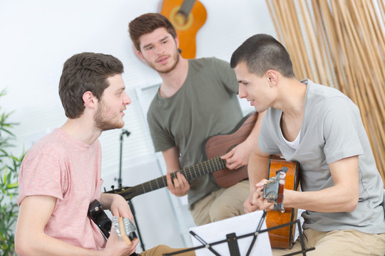 three friends rehearsing with guitar