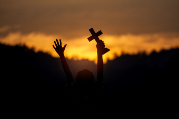 Children holding christian cross with light sunset background. silhouette concept