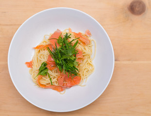 Overhead shot of a smoked salmon spaghetti with fresh herbs.