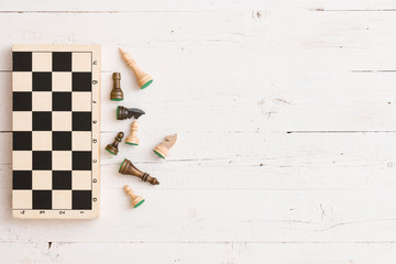 Top view on wooden chess board and chess figures on white wooden table background