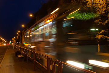 The motion of a blurred tram down the street in the evening.