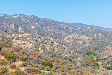 Fototapeta na wymiar Extremely dry hills in California mountains on hot summer day with sky for copy space