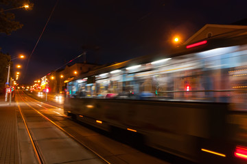 Naklejka na ściany i meble The motion of a blurred tram down the street in the evening.