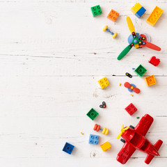 Above view on different small toy bricks, details, parts on white wooden table background