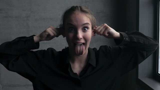 Young Woman Making Funny Faces and Pulling Her Ears